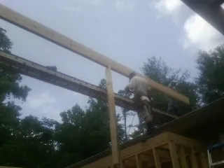 Carpenter setting a ridge beam over a new addition frame — Ice Dam Removal by Roofing Brothers in Pfeifer