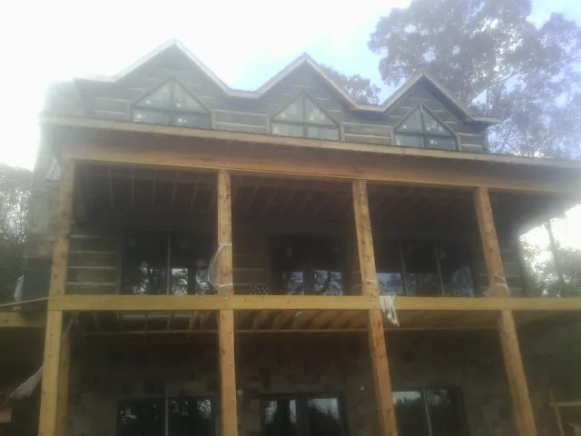 Dormers and porch framing on a large log home under construction — Roof Coating work by our crew in Pfeifer