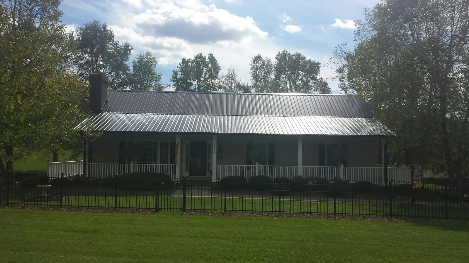 Gray metal roof on a brick ranch with a full width front porch — Gutter Guard Installation work by our crew in Pfeifer