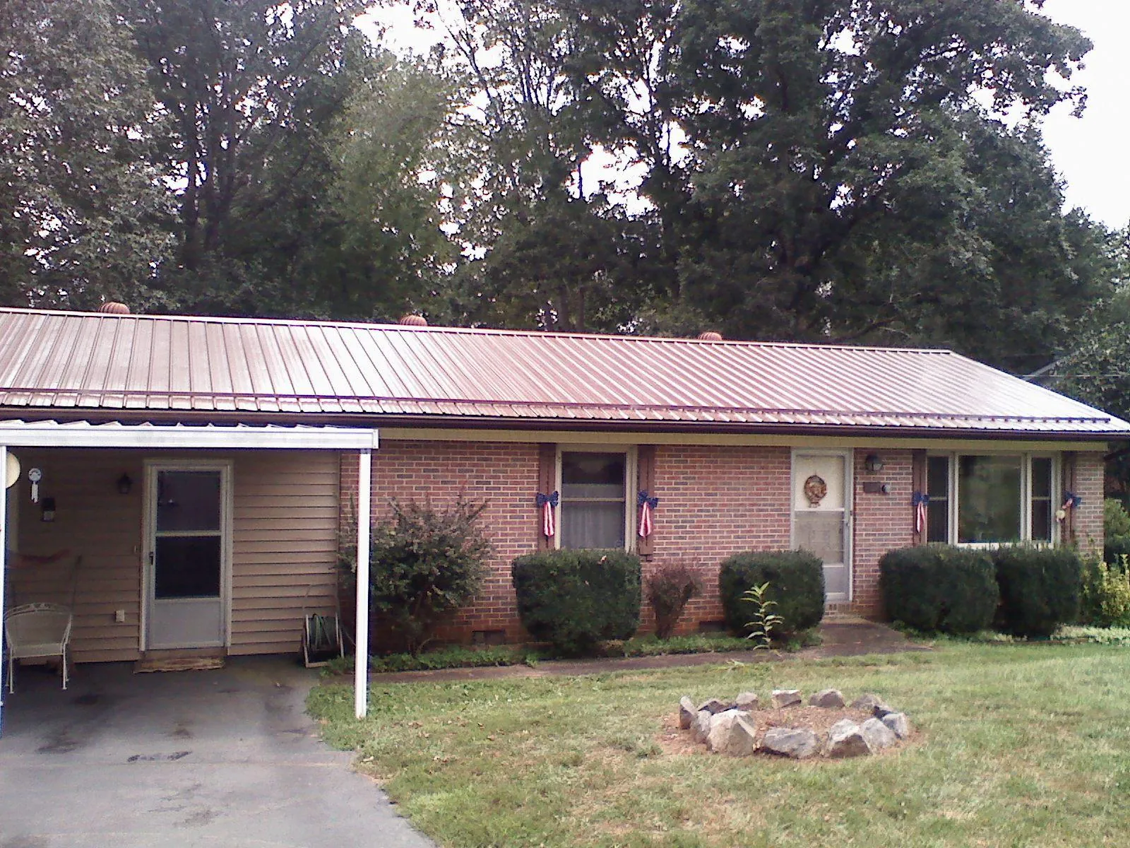 Bronze metal roof and carport on a brick ranch home — Roof Repair work by our crew in Pfeifer