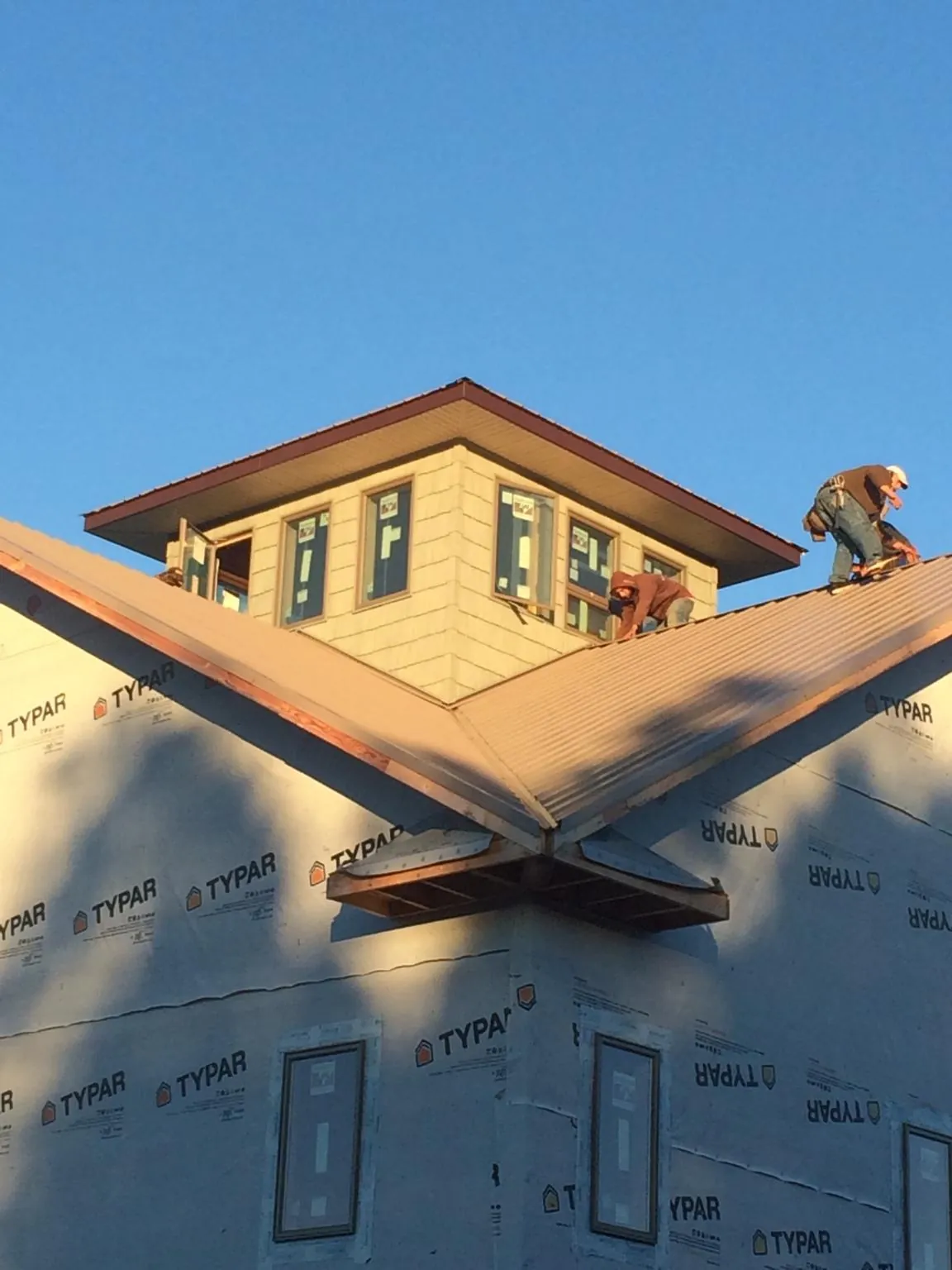 Roofers working around a rooftop cupola on a new metal roof at sunset — Roof Waterproofing in Pfeifer by Roofing Brothers